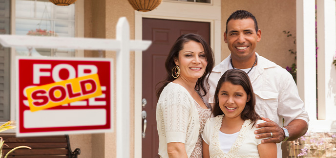 A happy family stands in front of their new home bought with a credit union loan.